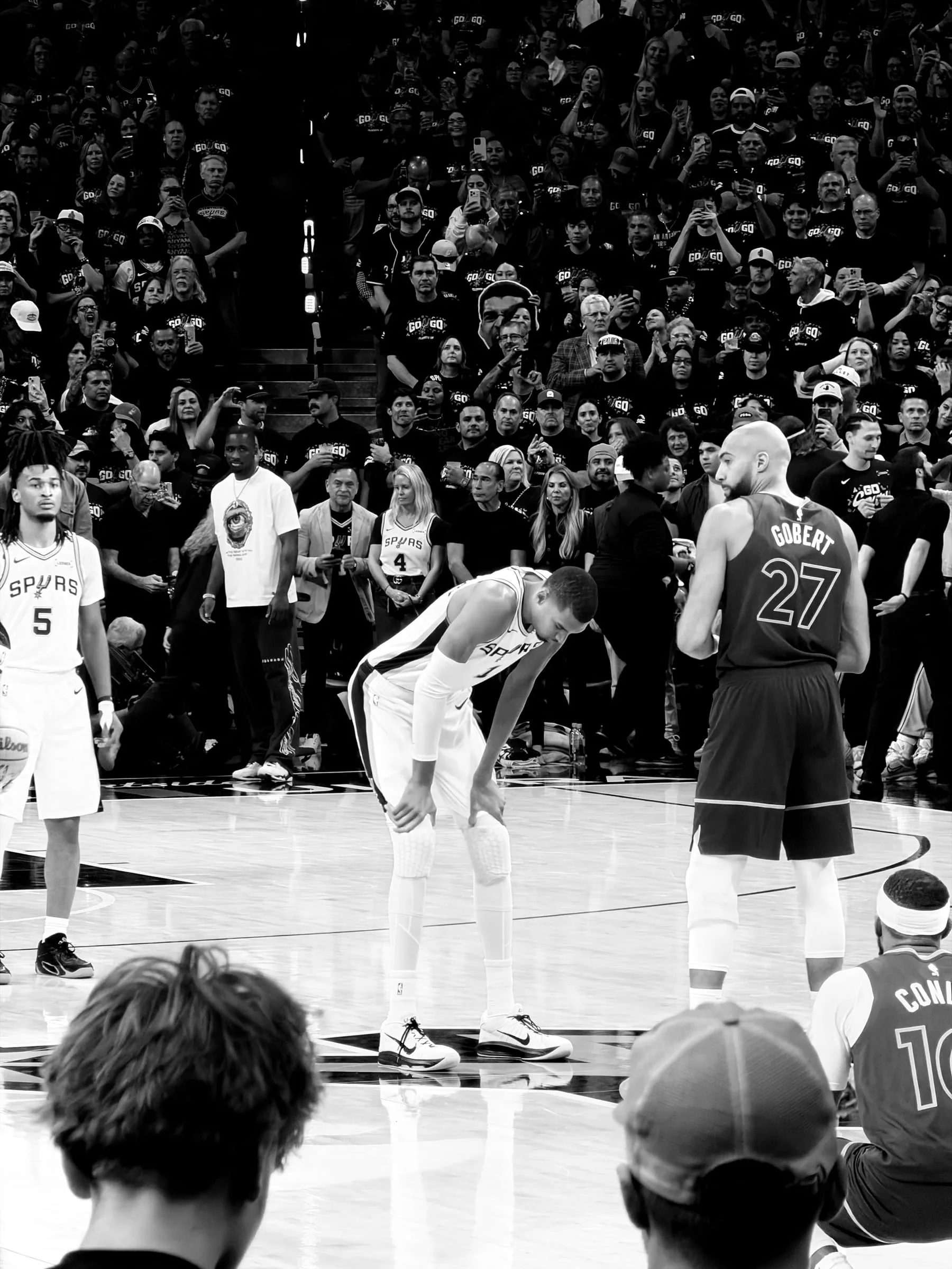 Victor Wembanyama #1 of the San Antonio Spurs catches his breath alongside rookie Stephon Castle #5 as the Minnesota Timberwolves' Rudy Gobert #27 and Mike Conley #10 wait during a dead-ball moment, Western Conference Semifinals, NBA Playoffs 2026, Frost Bank Center, San Antonio TX — press-credentialed editorial sports photographer Chauncey Scott